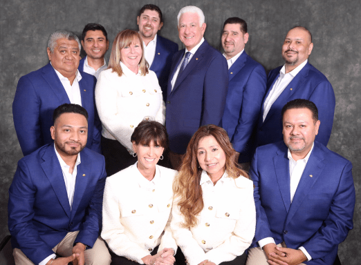 Fazio Cleaners leadership team posing together in professional business attire, with members wearing blue blazers and white shirts, smiling for a formal group portrait.