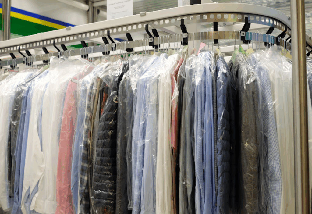 Professional dry cleaning carousel with dress shirts and garments in protective plastic showing dry cleaning vs hand cleaning quality